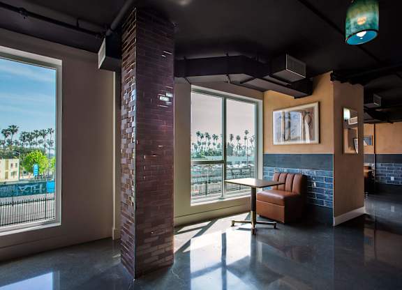 A room with a brick pillar and a window overlooking a pool.
