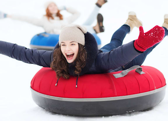 A person is lying on a red tube in the snow.