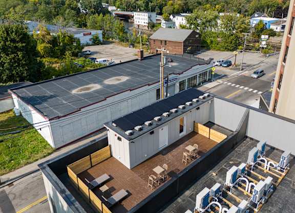 an aerial view of a building with a rooftop patio and tables and chairs