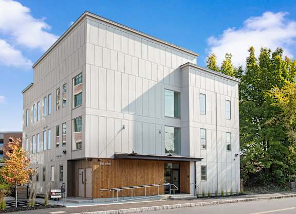 the exterior of a white building with a wooden facade