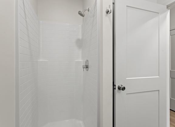 a bathroom with a shower and a white door