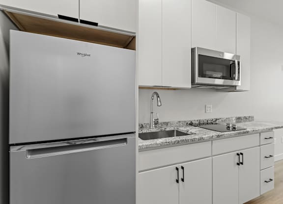 a kitchen with white cabinets and a stainless steel refrigerator and sink