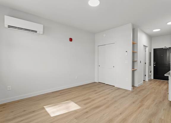 a living room and kitchen with white walls and wood floors