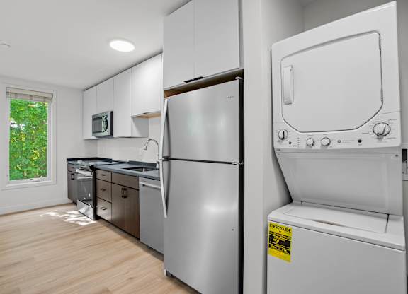 a white kitchen with a washer and dryer and a window