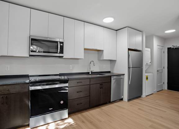 a kitchen with white cabinets and stainless steel appliances and a refrigerator