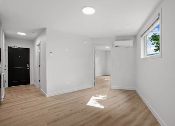 a living room with white walls and a window and wooden floors