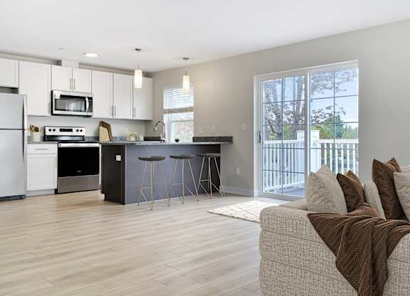 an open kitchen and living room with a sliding glass door to a balcony