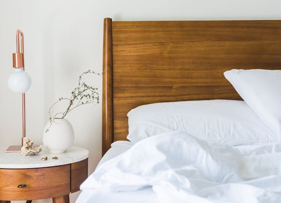 A bed with white pillows and a wooden headboard is in the image.
