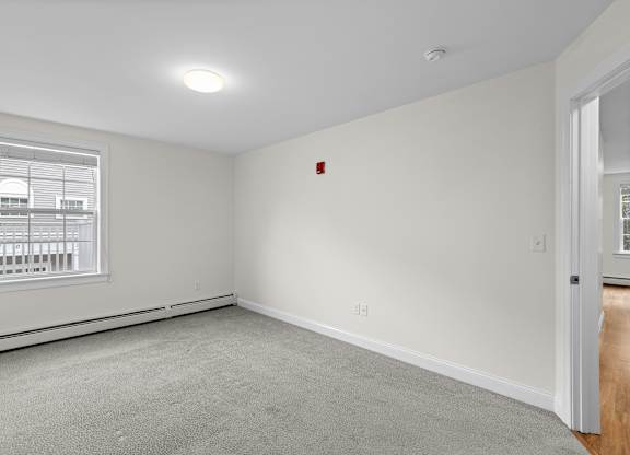 Empty bedroom with carpet and baseboard heating at Autumn Woods Apartments, Westbrook, ME