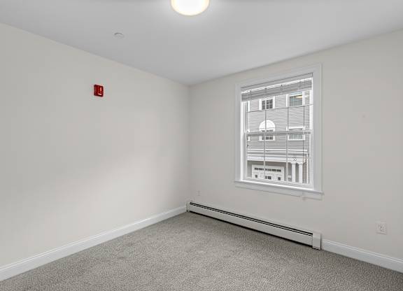 Empty bedroom with carpeting and window at Autumn Woods Apartments, Westbrook, 04092