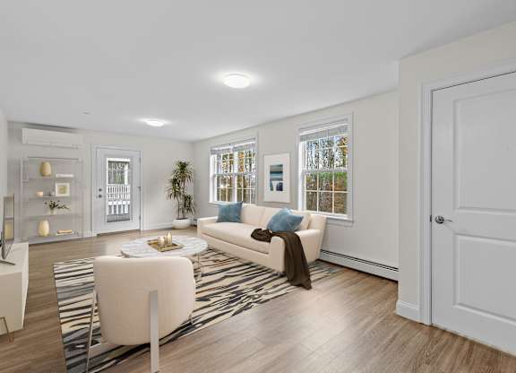 Bright living room with wood flooring and white sofa at Autumn Woods Apartments, Maine