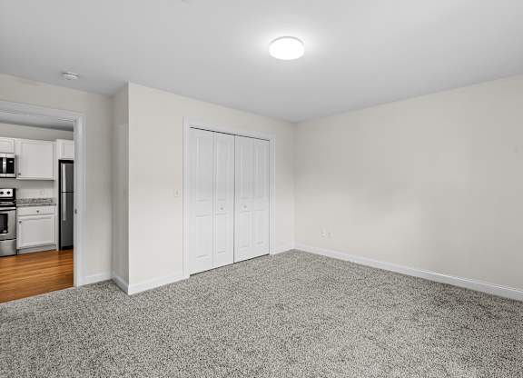 Carpeted room with kitchen view at Autumn Woods Apartments, Westbrook, 04092