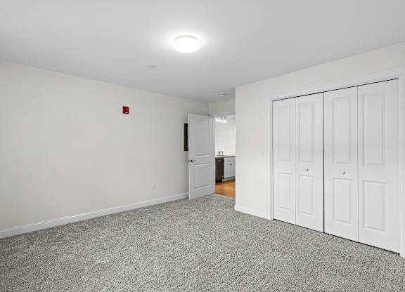 Carpeted room with closet at Autumn Woods Apartments, Westbrook, Maine