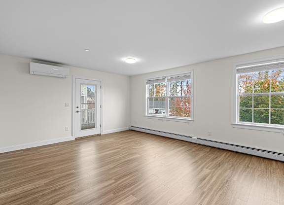 Spacious living room with wood flooring and windows at Autumn Woods Apartments, Westbrook, ME 04092