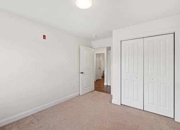 A white door is closed and another is open in a room with a carpet.