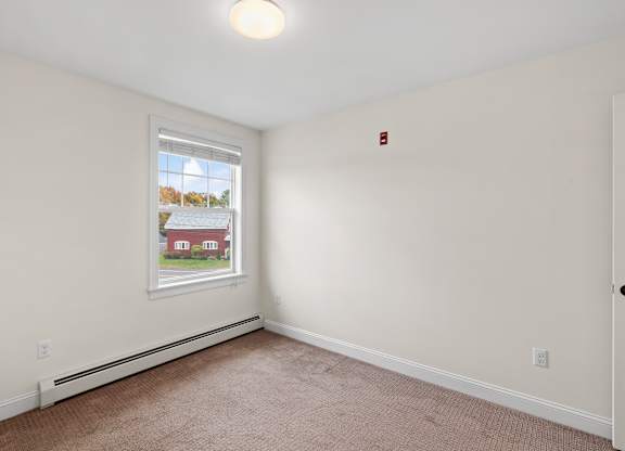 A room with a window showing a view of a house outside.