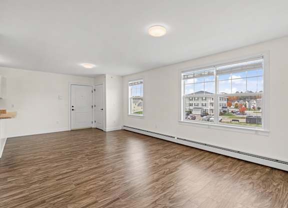 A room with a window showing a street view and a wooden floor.