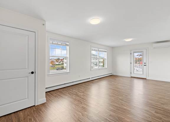 A room with a white door and a window with a view of a house and trees.