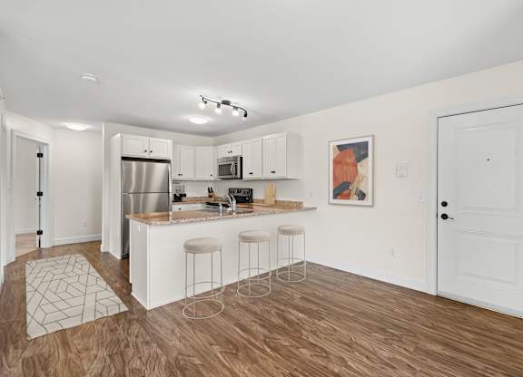 a living room with a kitchen and a bar with three stools