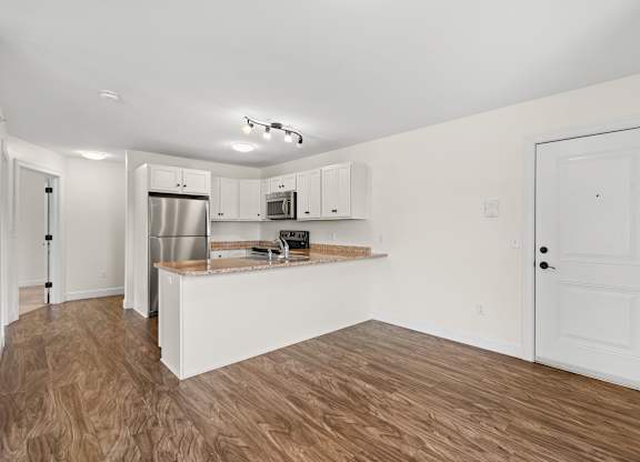 A kitchen with white cabinets and a wooden floor.
