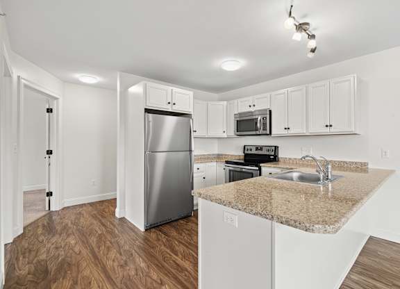 A kitchen with white cabinets and a granite countertop.