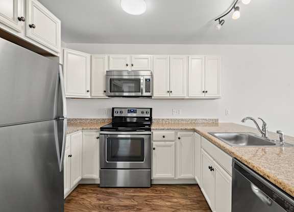 A kitchen with a stainless steel refrigerator and a microwave above the stove.