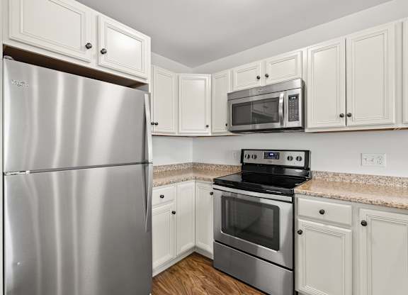 A kitchen with a stainless steel refrigerator, microwave, and oven.