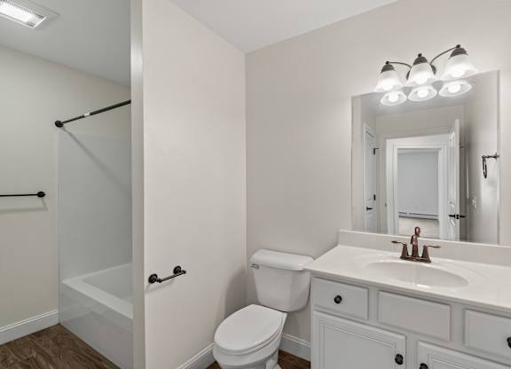 A white bathroom with a toilet, sink, and mirror.