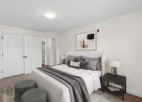 a bedroom with white walls and a white bed with gray pillows