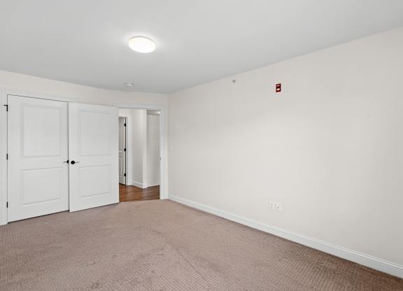 A room with a white door and a red fire alarm on the wall.
