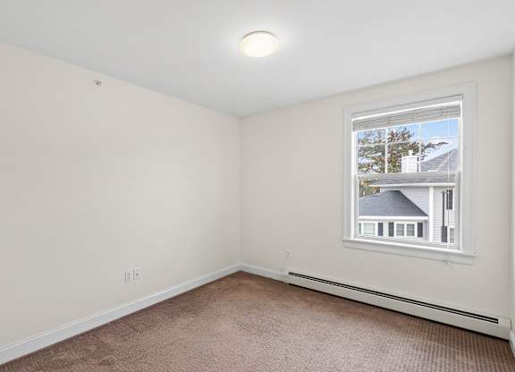 A room with a window showing a house outside.