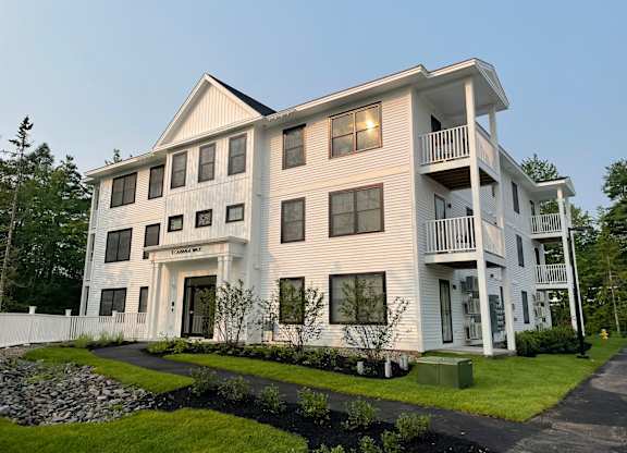A large white building with a balcony on the second floor.