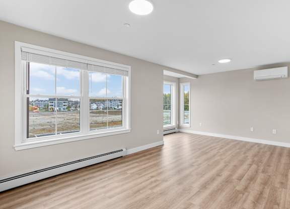 Bright living room with LVP flooring, large windows, and modern climate control.