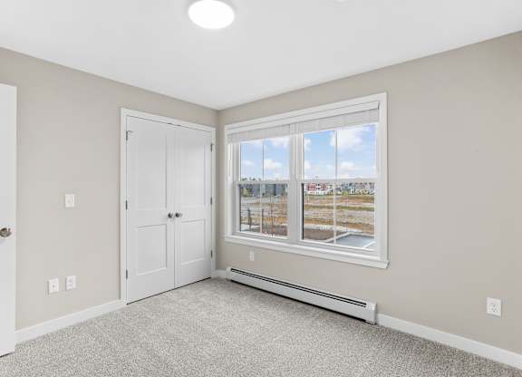 Spacious bedroom with plush carpeting, generous closet space, and natural light from a large window.
