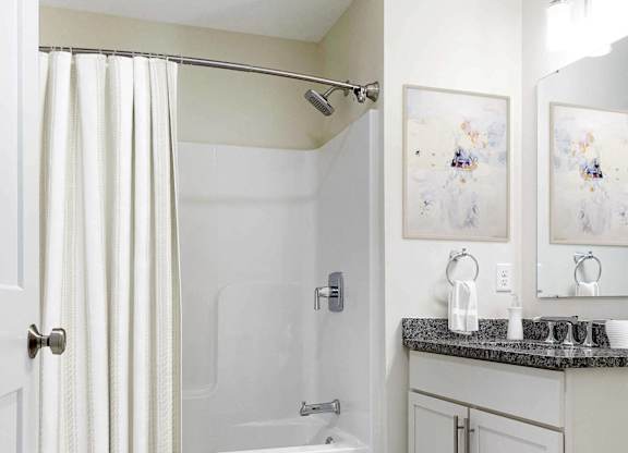 a white bathroom with a shower and a sink