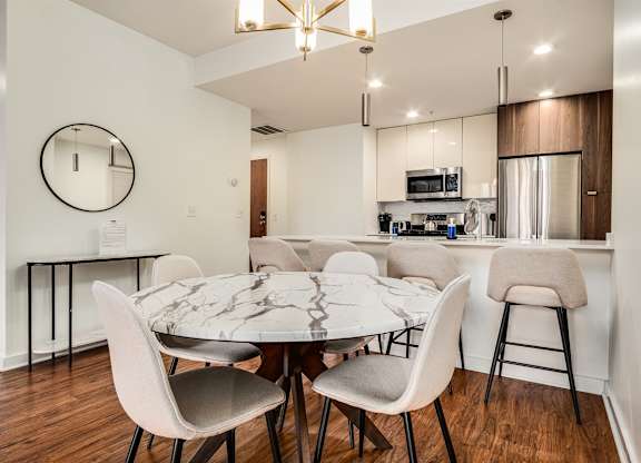 A modern dining room with a round mirror and a marble table.