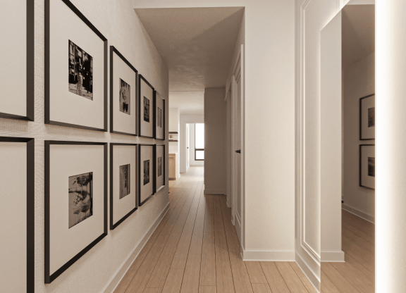 a hallway with black and white photos on the wall and wooden floors at Chateau on Wells, Chicago, IL