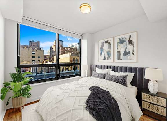A bedroom with a large bed and a view of the city at Chateau on Wells, Chicago, IL