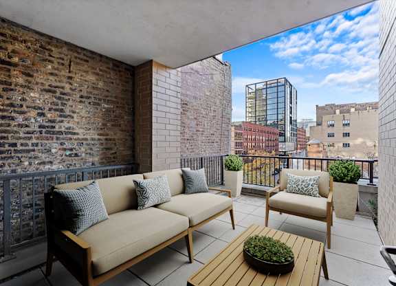A balcony with a couch, chairs, and a table with a plant on it at Chateau on Wells, Chicago, 60654