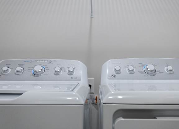 Two white front loading washing machines with blue and silver knobs.