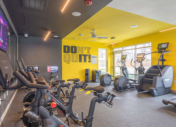 A gym with exercise bikes and a yellow wall with the words "Don't Quit!" on it.