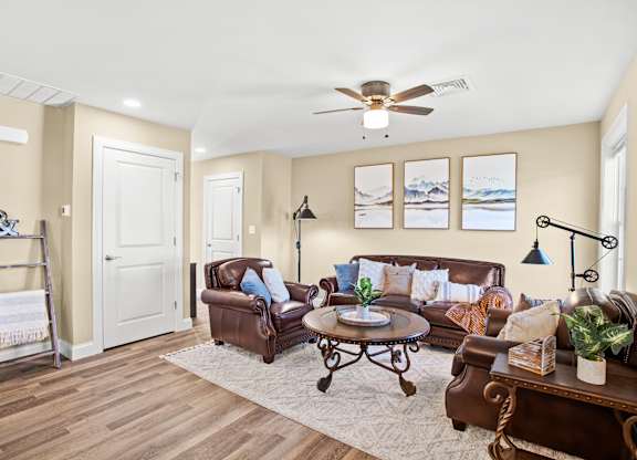 a living room with leather furniture and a ceiling fan