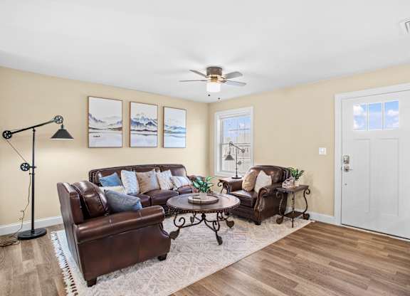 a living room with leather furniture and a ceiling fan