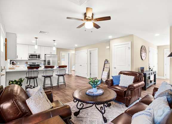 a living room with leather furniture and a kitchen in the background