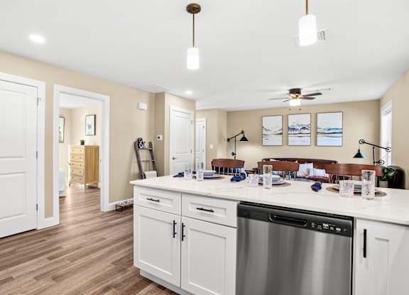 an open kitchen and living room with a large counter top and a dishwasher