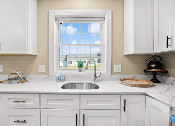 a white kitchen with a sink and a window