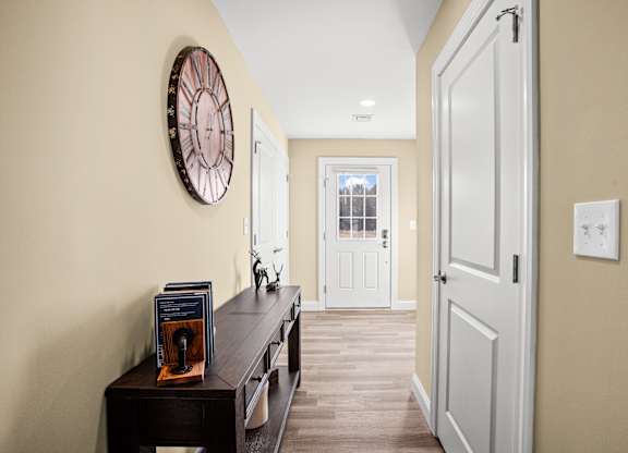 a hallway with a desk and a clock on the wall and a white door