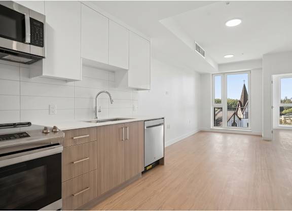 A kitchen with wooden floors and white cabinets.