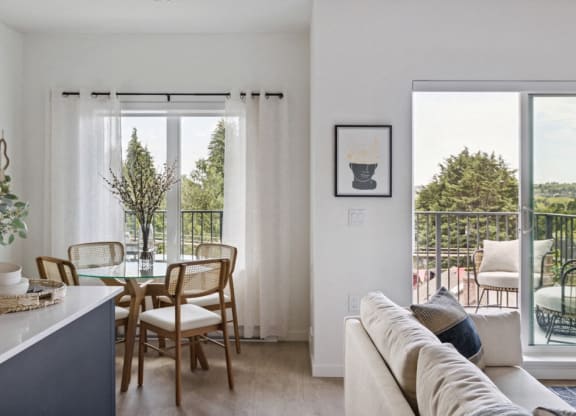a living area with a couch and a table with chairs and a balcony