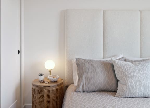 a bed with pillows and a nightstand with a lamp on it